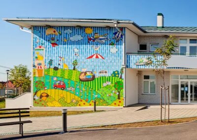 Galerie-Motiv Sonderbau: Kitas, Kindergarten, Hort (Bild eines bunt bemalten Gebäudes mit Hof zum Spielen).